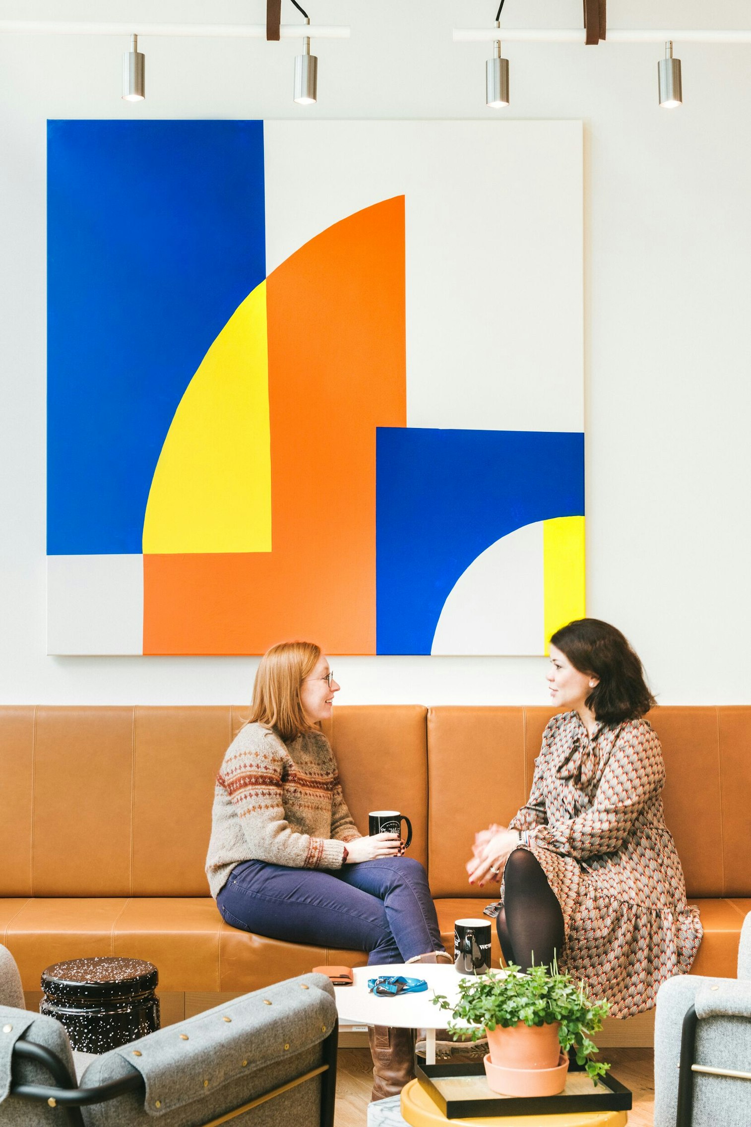 Wework Coworking And Office E Two Women On Tan Couch With Painting 4 By 3